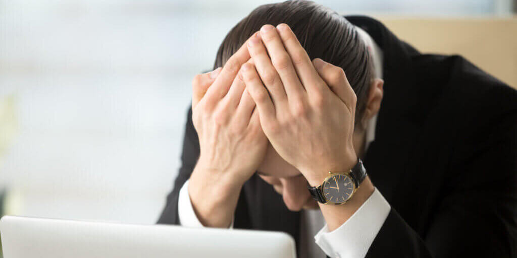 Businessman sitting head in hands shocked because of company bankruptcy, market crash, loss of savings. Young man in despair after receiving dismissal notice, confiscation of property through debt
