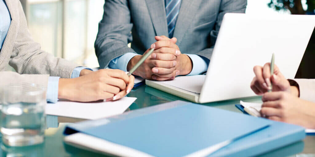Close-up of hands of boss at workplace with laptop and hands of two females near by