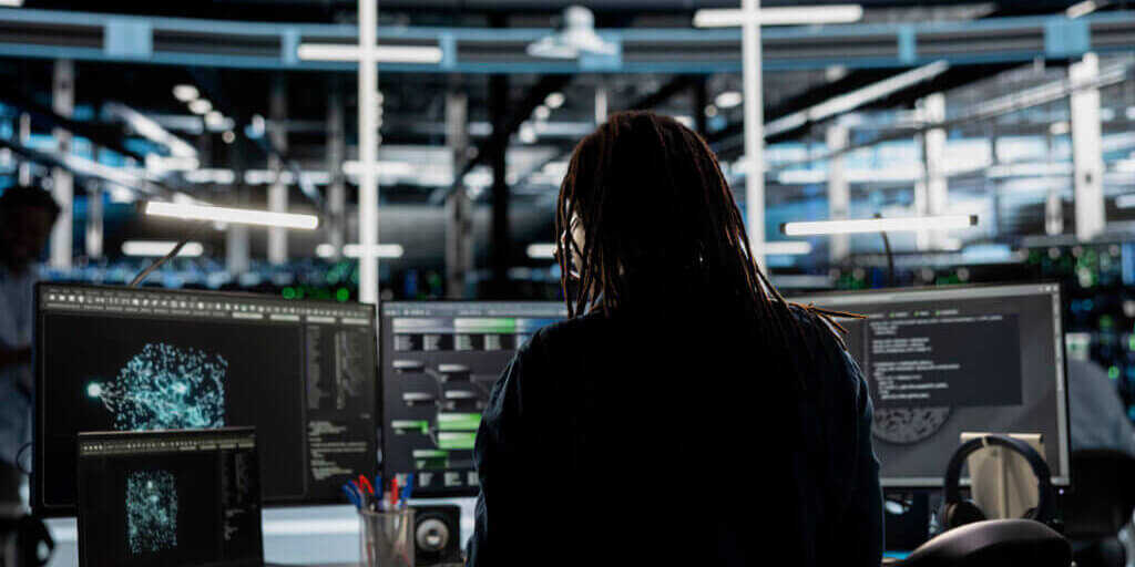 Data center admin looks at AI visualization dashboard on laptop to pinpoint equipment performance issues. Server farm specialist looks at data analysis graph on notebook to reduce hardware failures
