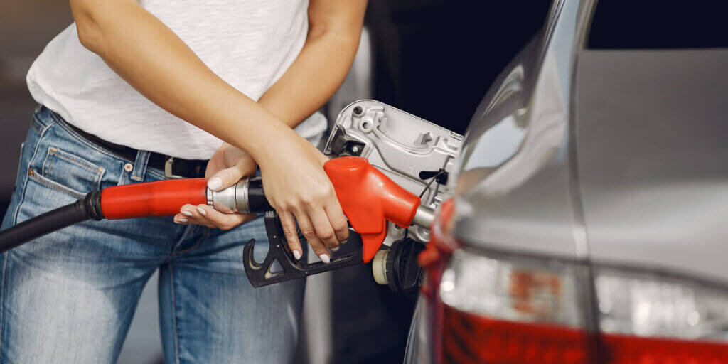 Woman on a gas station. Lady in a white t-shirt. Woman near the car.
