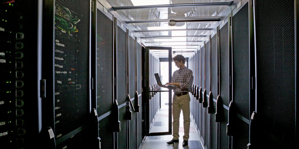 37956175 - technician with laptop, checking aisle of server storage cabinets in data center