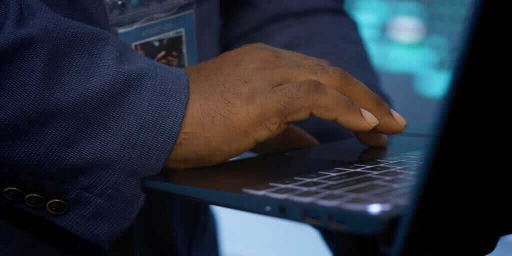 IT technician working on notebook in data center, overseeing server operations. Extreme close up shot of man ensuring optimal performance and data integrity in server hub, camera A
