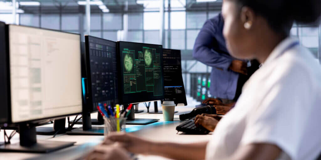 Computer scientist reconfiguring server farm to optimize it for data processing requirements of customers. African american woman working to ensure data center equipment operates efficiently