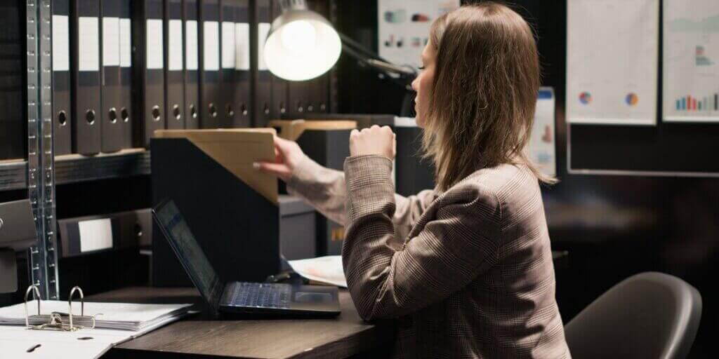 Caucasian policewoman inspecting evidence, reviewing records, and utilizing technology in a well-organized office space. Dedicated investigator analyzes witness statements and records to solve crime.