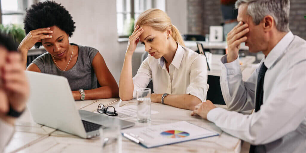 Group of business colleagues having a headache while working on laptop and trying to solve the problems during a meeting.