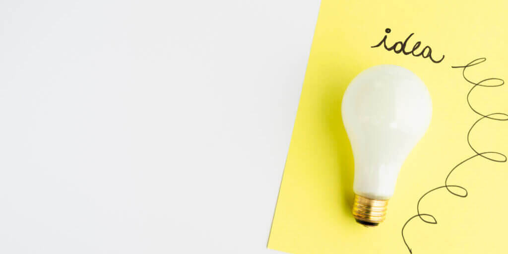 idea-text-written-adhesive-note-with-light-bulb-white-background